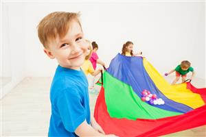 Boy holding up a parachute with other children