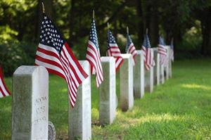 A row of simple gravestones each adorned with an American flag